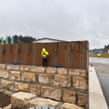 Die Lärmschutzwand wird auf einer Mauer aus groben Steinen aufgebaut